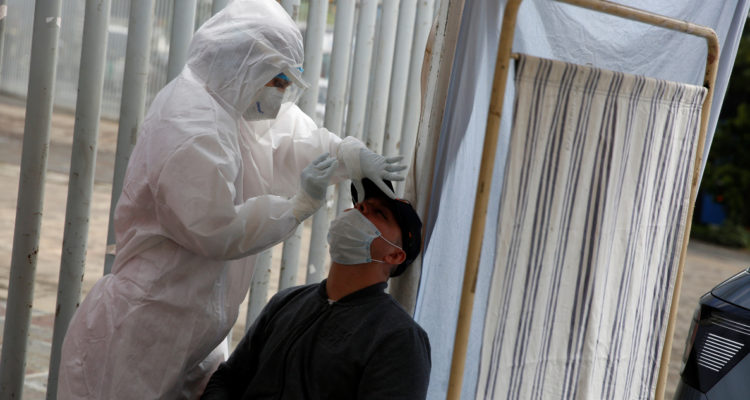 Una funcionaria de salud realiza PCR a un hombre en medio de las nuevas noticias de la flurona.
