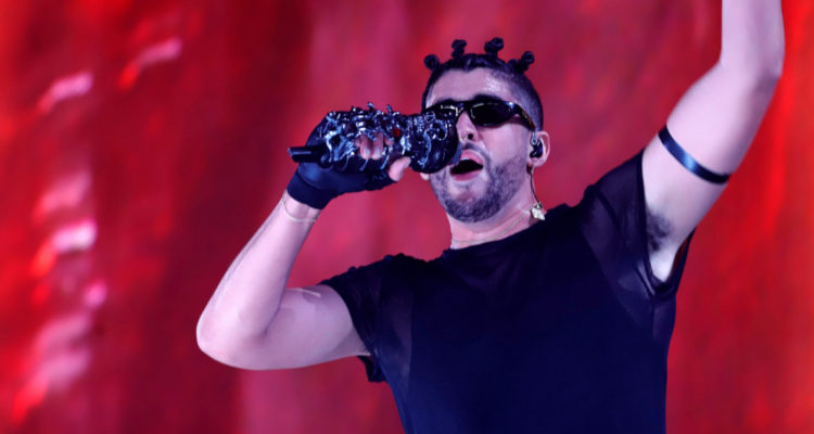 Bad bunny usa lentes de sol mientras canta en uno de sus conciertos.