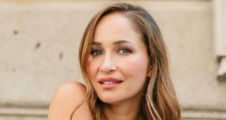 La bailarina Francini Amaral sonríe a la cámara mientras apoya su mentón en un hombro.