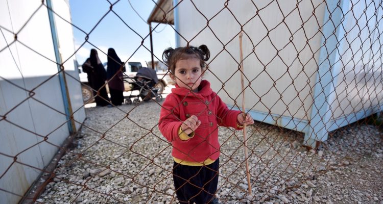 Una niña junto a dos esposas de soldados del EI.