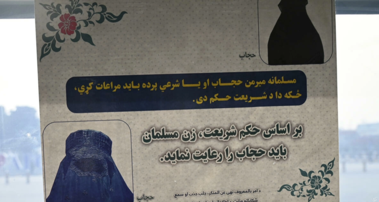 Un afiche indicando a las mujeres cómo deben vestir en un portón del aeropuerto de Kabul, Afganistán.