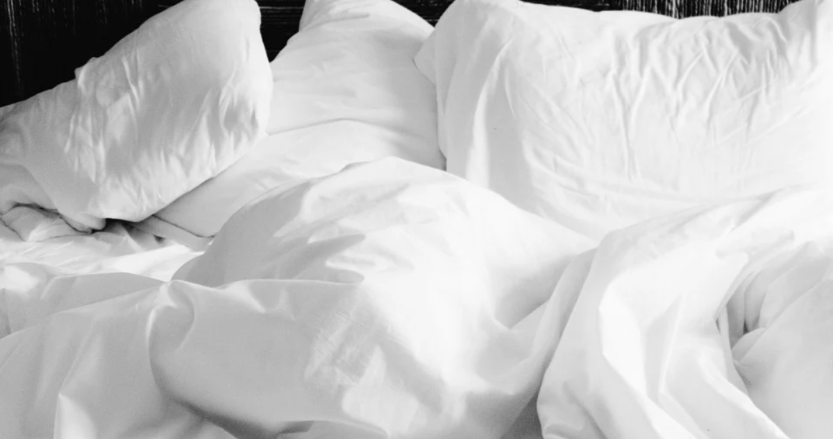 Cama, sábanas y almohadas blancas