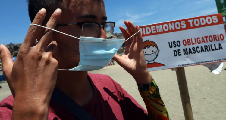 Joven se pone mascarilla en playa