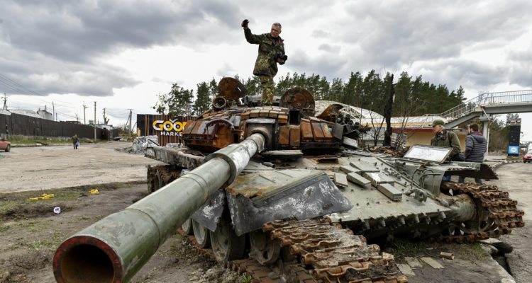Un hombre sobre un tanque ruso destruido en Ucrania.
