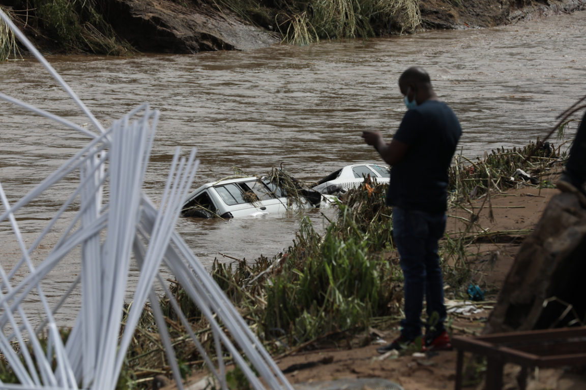 Un hombre observa un automóvil llevado por una crecida de un río.
