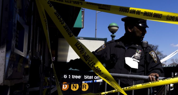 Un policía acordonando el lugar del crimen.