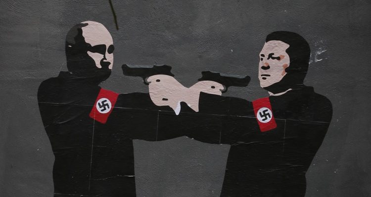 Un grafiti de Zelenski y Putin apuntándose mutuamente, ambos con esvásticas en sus brazos.