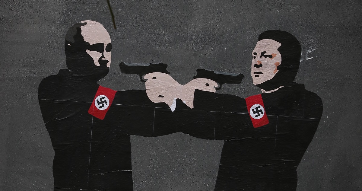 Un grafiti de Zelenski y Putin apuntándose mutuamente, ambos con esvásticas en sus brazos.