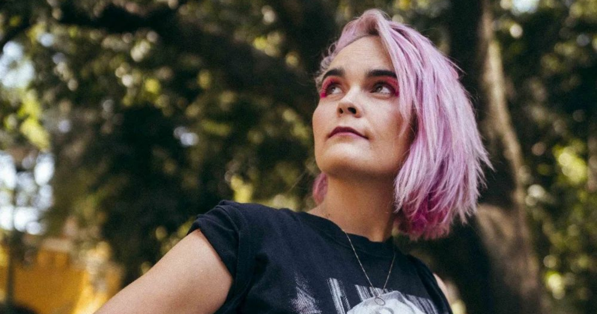 Camila Moreno posa con las manos en la cintura mientras mira hacia arriba. Se encuentra en un parque lleno de árboles. La artista fue uno de los ganadores de los Premios Pulsar 2022.