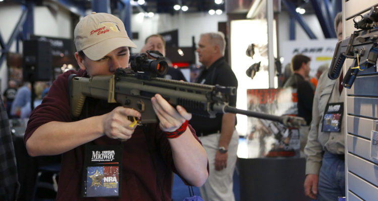 Un joven prueba un arma en una exhibición de la Asociación Nacional del Rifle, en EEUU.