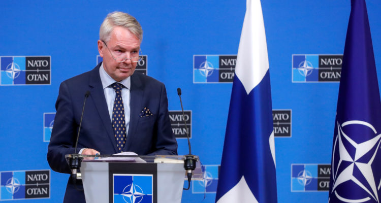 El ministro de exteriores finlandés junto a una bandera de su país y otra de la OTAN.