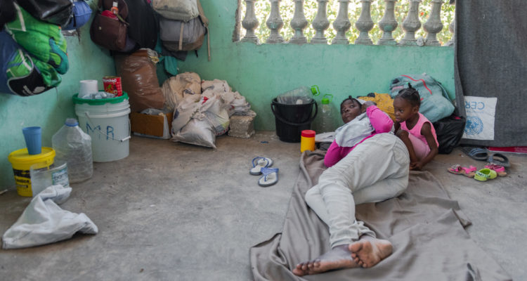 Una mujer y su hija descansan junto a algunas de sus pertenencias en un albergue improvisado para desplazados internos por la guerra de pandillas, hoy, en Puerto Príncipe (Haití).