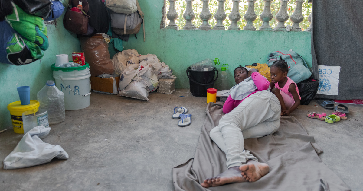 Una mujer y su hija descansan junto a algunas de sus pertenencias en un albergue improvisado para desplazados internos por la guerra de pandillas, hoy, en Puerto Príncipe (Haití).