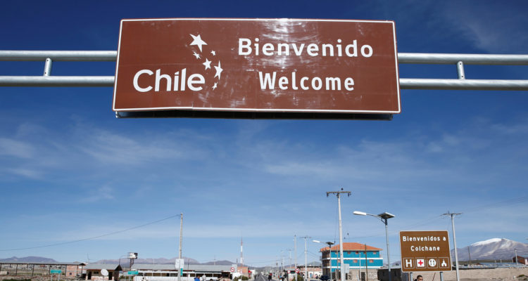 Migrantes caminan bajo un cartel que señala la entrada a Chile, el 13 de febrero de 2022, en los alrededores de la fronteriza comuna de Colchane (Chile), en una fotografía de archivo.