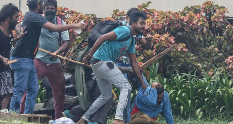 Manifestantes pro-gobierno golpean a manifestantes anti-gobierno.