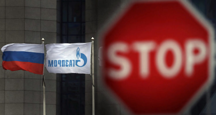 Una bandera rusa y una de Gazprom junto a un signo pare.