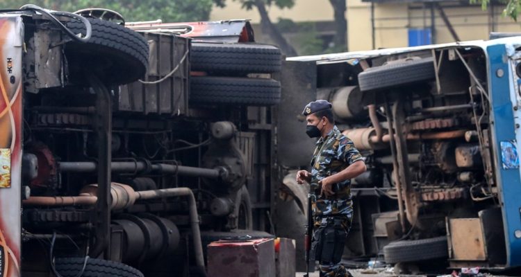 Un policía junto a dos camiones volcados en Sri Lanka.