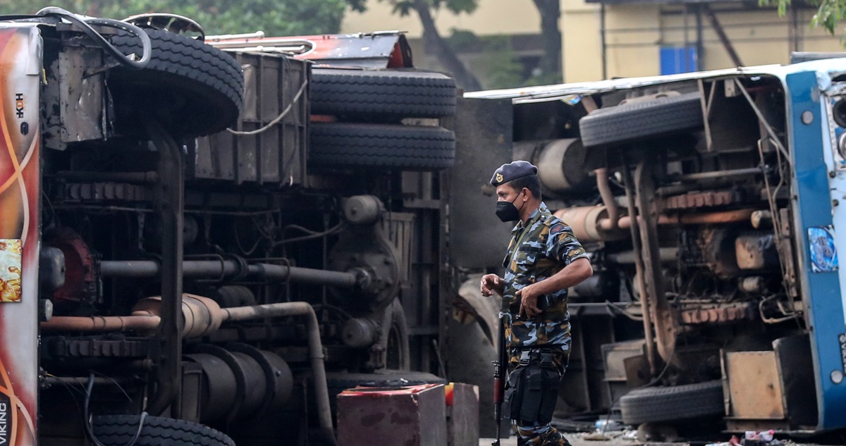 Un policía junto a dos camiones volcados en Sri Lanka.