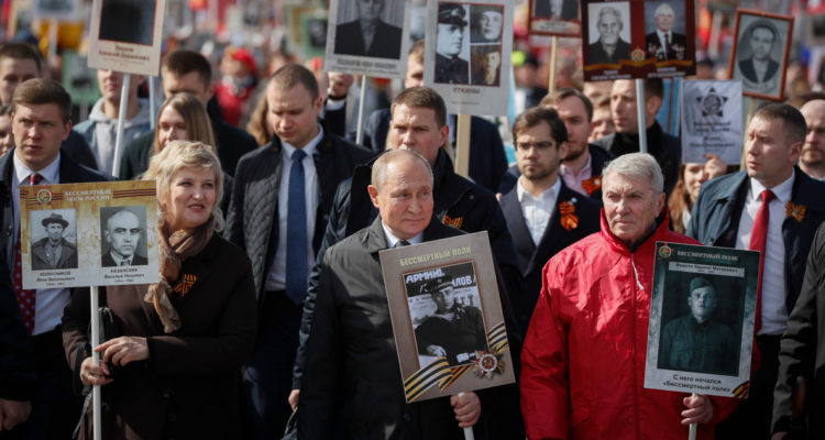Vladimir Putin y otros ciudadanos rusos portando fotografías de familiares que participaron en la Segunda Guerra Mundial.