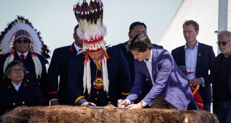 El primer ministro canadiense, Justin Trudeau, firma el acuerdo de compensación con el líder indígena.