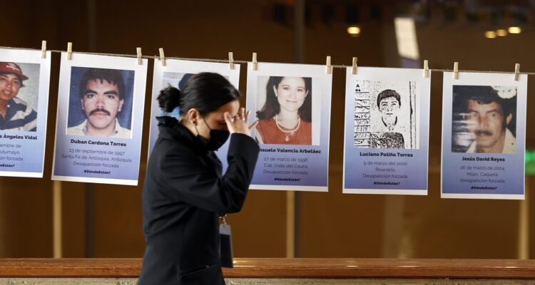 Asistentes a la biblioteca Virgilio Barco observan una exposición con los rostros de las víctimas de secuestro, durante el proceso conocido como el “Caso 01” de la JEP.