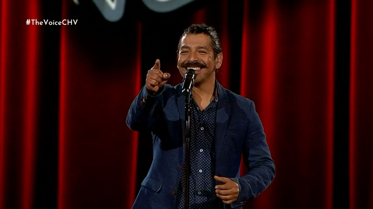 Hernán Pelegrí sonriendo mientras apunta al jurado en The Voice.