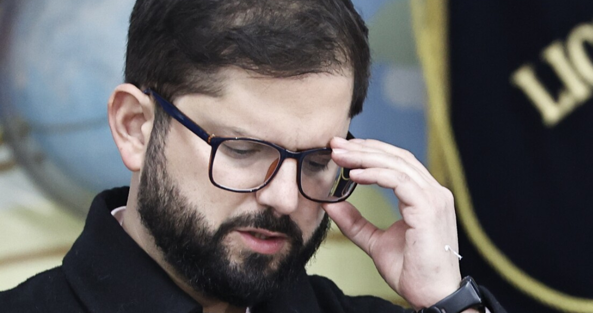 Gabriel Boric, presidente de Chile, mirando hacia abajo mientras se toma los lentes.