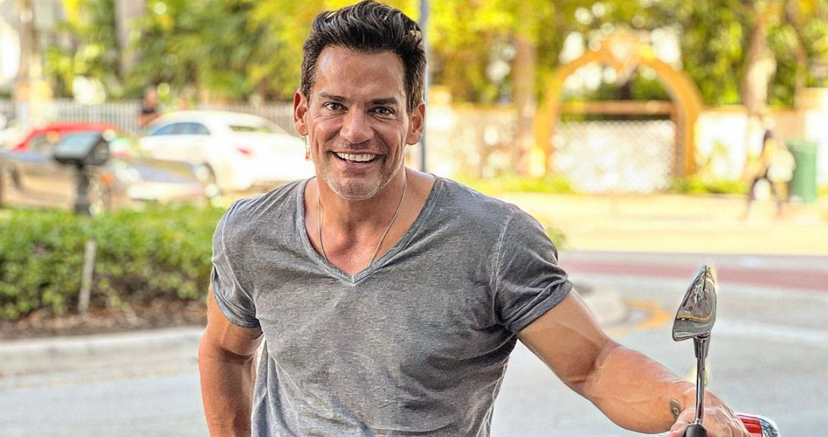 El actor Cristián de la fuente posa al lado de una moto sonriendo. El intérprete protagonizará una peícula navideña.