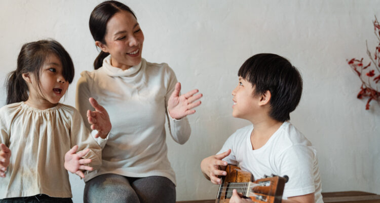 Una madre junto a dos niños pequeños cantando. Las canciones pueden funcionar a la hora de mejorar la pronunciación de la R.