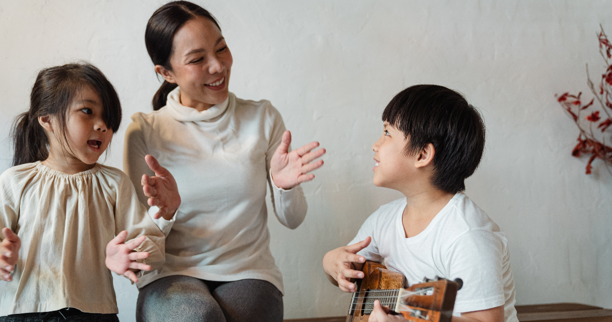Una madre junto a dos niños pequeños cantando. Las canciones pueden funcionar a la hora de mejorar la pronunciación de la R.