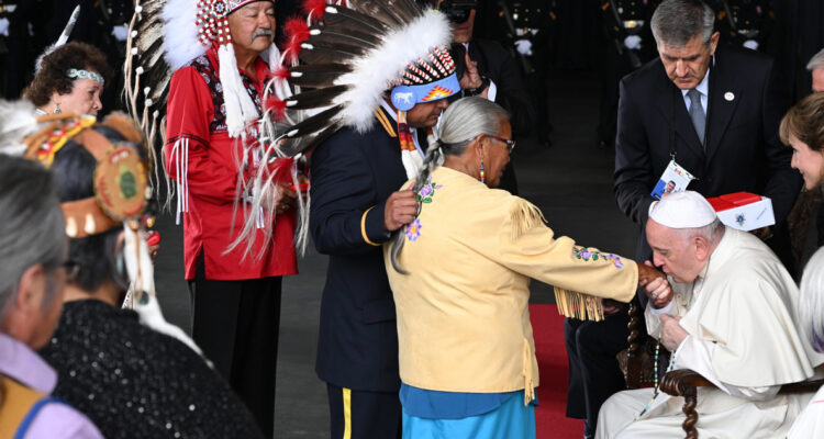El papa besa la mano de una representante indígena en su visita a Canadá.