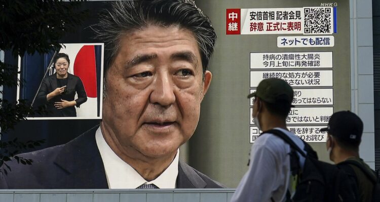 Transeúntes viendo noticias sobre la muerte de Shinzo Abe una pantalla gigante a plena calle.