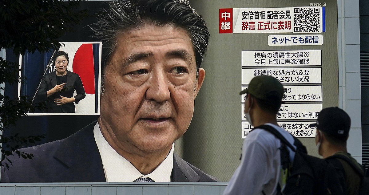 Transeúntes viendo noticias sobre la muerte de Shinzo Abe una pantalla gigante a plena calle.