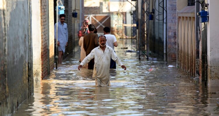 Un hombre camina con el agua hasta las caderas por las calles de una ciudad pakistaní.