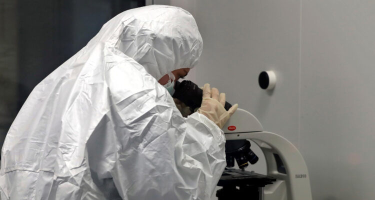 Un funcionario de la salud investigando en un microscopio.