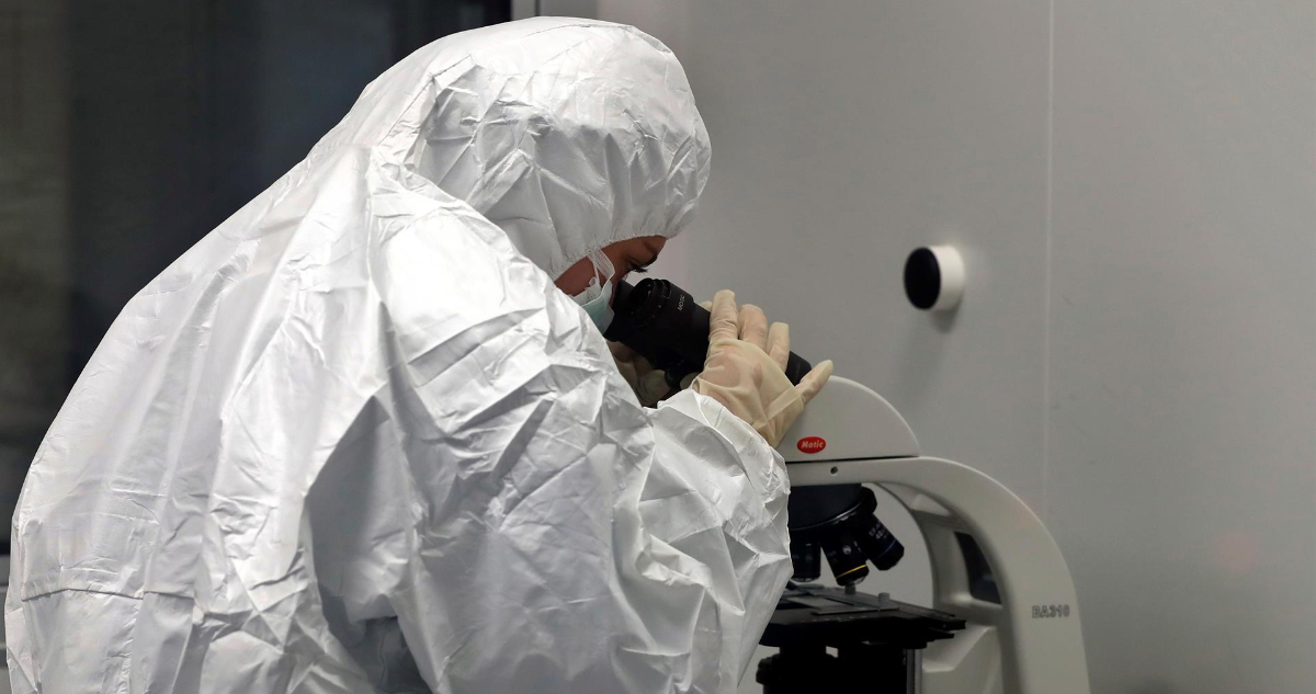Un funcionario de la salud investigando en un microscopio.