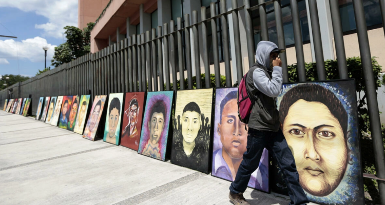 Foto de archivo del 24 de septiembre de 2015. Un estudiante pasa junto a los retratos de algunos de los 43 estudiantes desaparecidos de la escuela rural de maestros de Ayotzinapa.