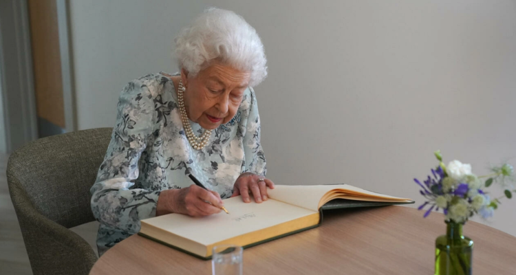 La reina Isabel II firma en el libro de honor de un hospicio cuyo nuevo edificio inauguró oficialmente.