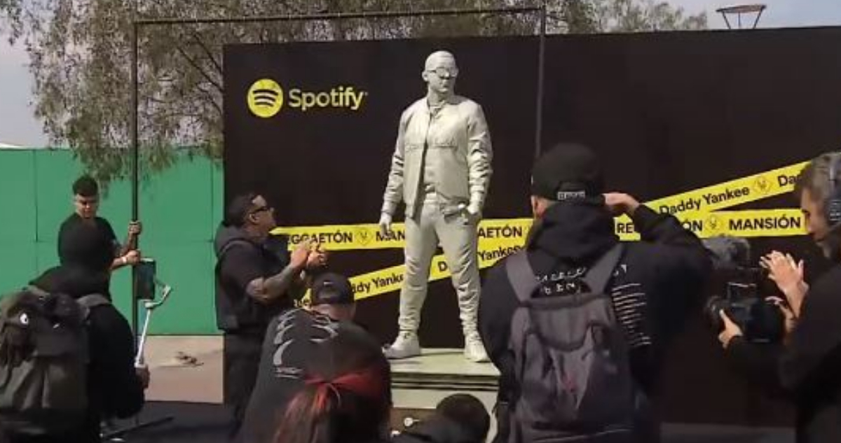 El cantante Daddy Yankee mirando su estatua.