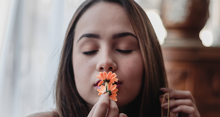 Mujer oliendo flores. Las mascarillas serían un inesperado aliado de los alergicos