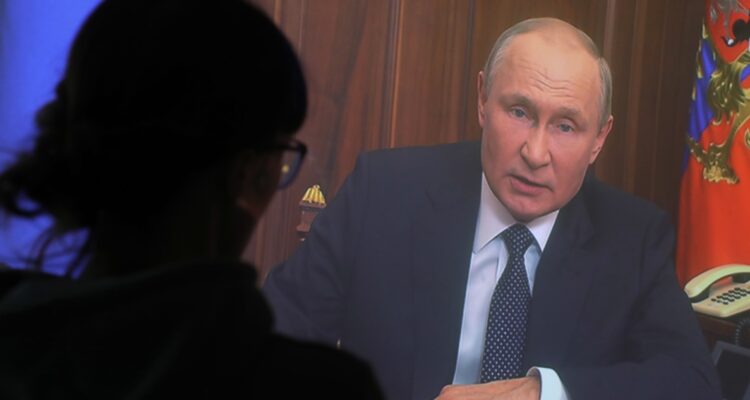 Una persona ve la transmisión del discurso de Vladimir Putin.