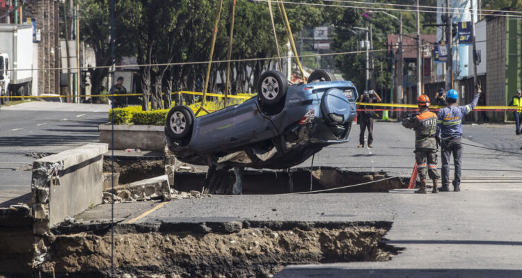 Socorristas y trabajadores sacan un vehículo de un socavón en el municipio guatemalteco de Villa Nueva.