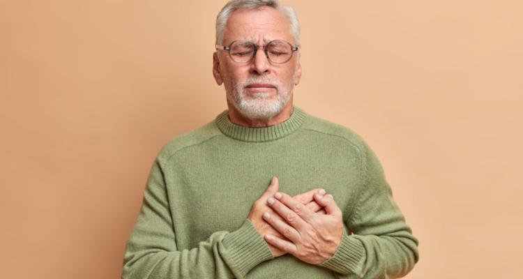 Hombre mayor con las manos en el pecho y expresión de dolor en el rostro. Cientificos chilenos buscan aclarar si la infección por Covid puede estar relacionada con el riesgo de desarrollar enfermedades al corazón o cardiovasculares