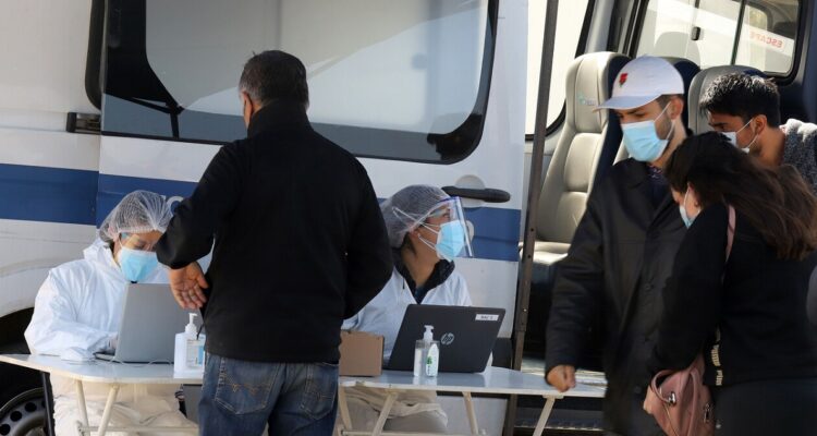 Funcionarios sanitarios tomando pruebas PCR en un puesto móvil.