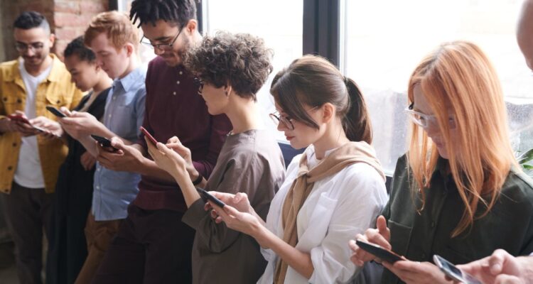 Grupo de adolescentes y jovenes usando su celular. Estudio analizó los efectos de no usar dispositivos en la salud mental de los jóvenes
