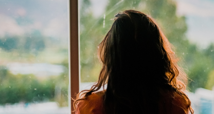 Mujer mirando por una ventana de espaldas. ¿Qué es la depresión endógena y cómo reconocerla?