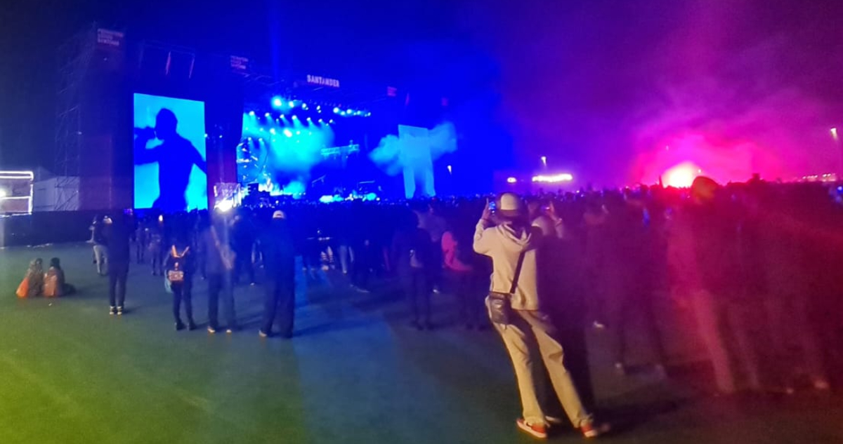 El público de Travis Scott presenciando el concierto mientras una bemgala está encendida en medio de la multitud.