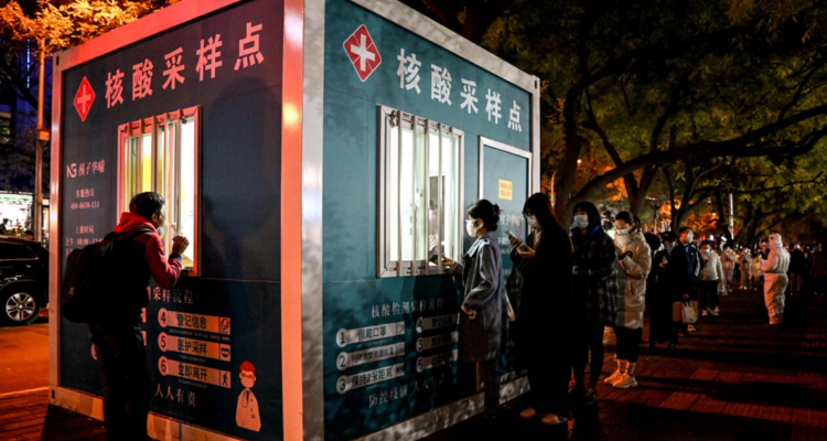 Decenas de personas guardan cola ante un punto de reparto de pruebas de detección del covid-19.