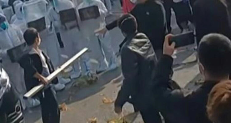 Imagen tomada de un video publicado el 23 de noviembre de 2022, donde se ve a trabajadores de la fábrica Foxconn de Zehngzhou, en el centro de China, enfrentándose a policías y a gente con trajes de protección.