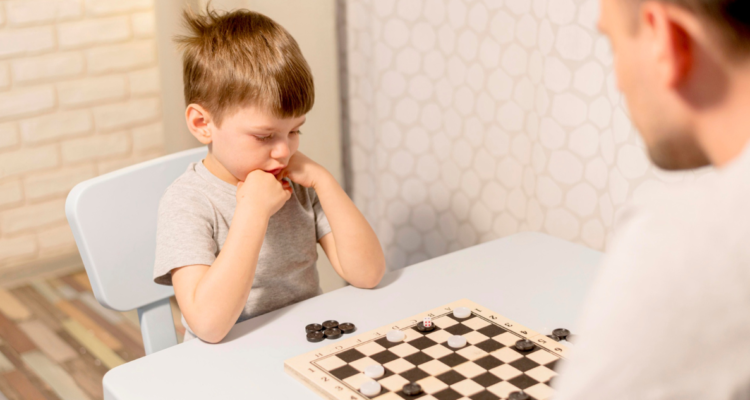 Niño jugando damas con su padre. Estudio descubrió que los niños tienen aprendizaje más rápido que los adultos